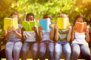 Five children sitting in a line reading books.