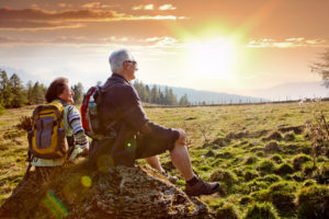 An older couple watching the sunrise on a hike.