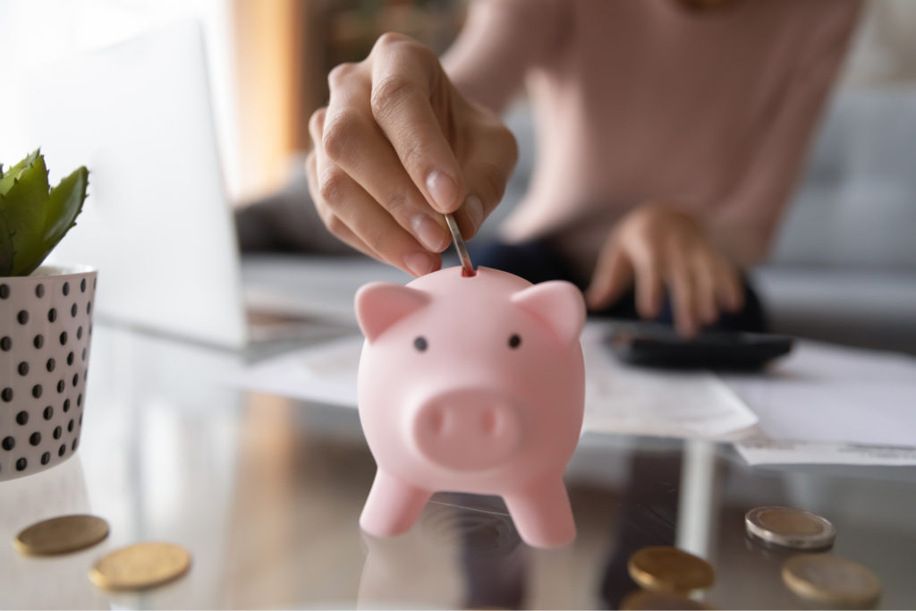 A woman placing money in a piggy bank.