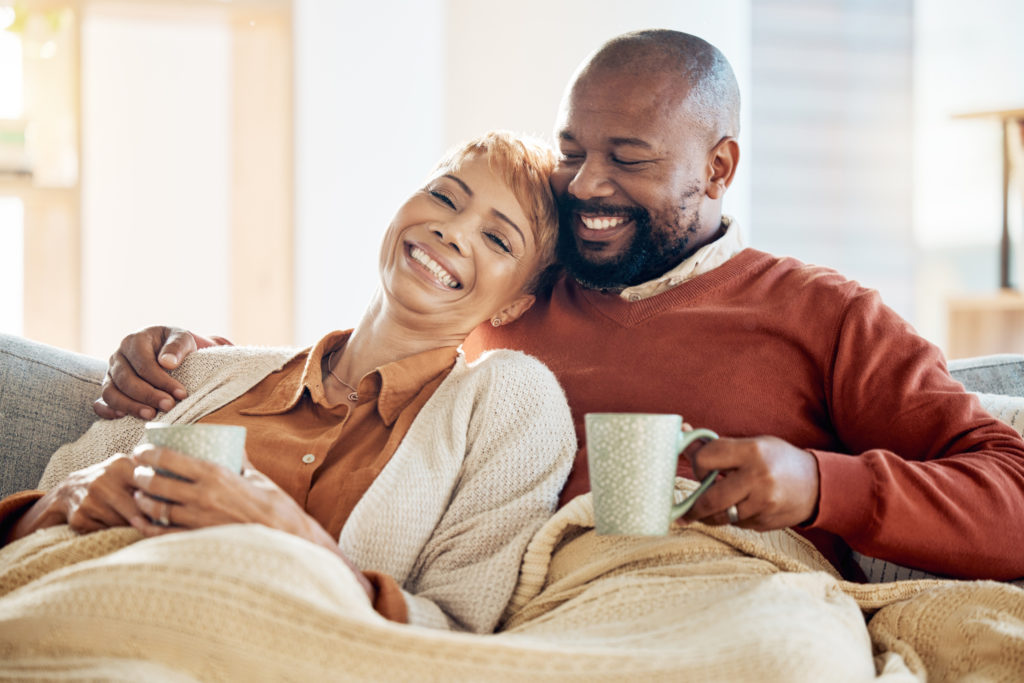 A couple laughing together while drinking coffee.