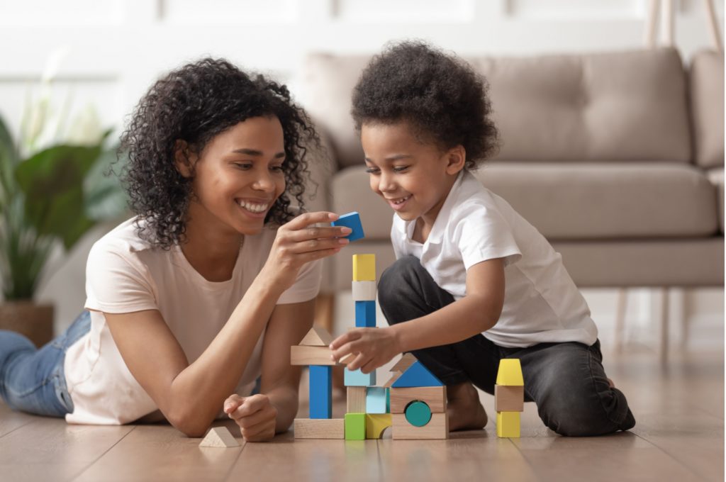 A mother and son building a tower from wooden blocks.