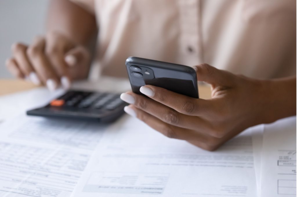 A woman using a calculator while reviewing paperwork.