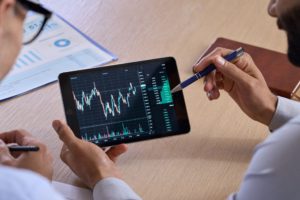 Two people looking at a trading chart on a tablet.