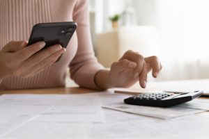 A woman using a phone and calculator.