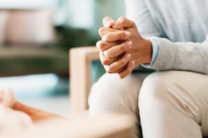 A woman sitting with her hands clasped.