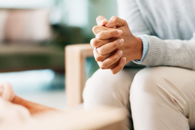 A woman sitting with her hands clasped.