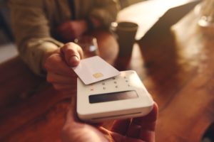 A person using their debit card to pay in a café.