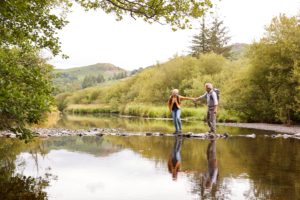 A couple walking across stepping stones.